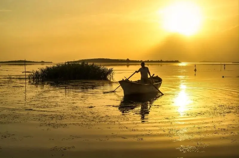 Khung cảnh thuyền đánh cá trên sông lúc hoàng hôn, đầy màu sắc.