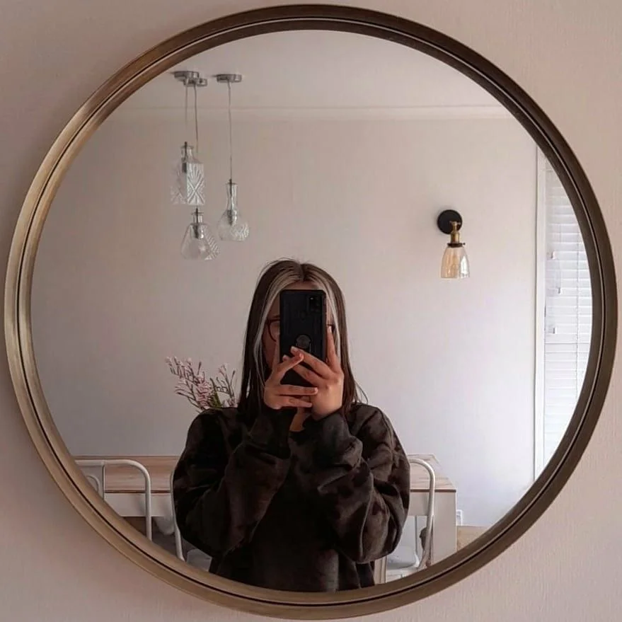 Photo of a girl taken in front of the mirror covers her face like a novel that has not been opened.